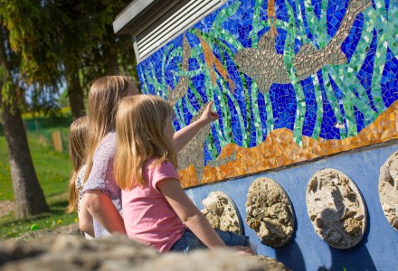 Kinder sitzen vor einer Mosaikwand
