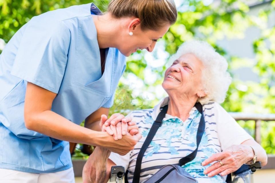 Pflegerin hält die Hand einer Seniorin