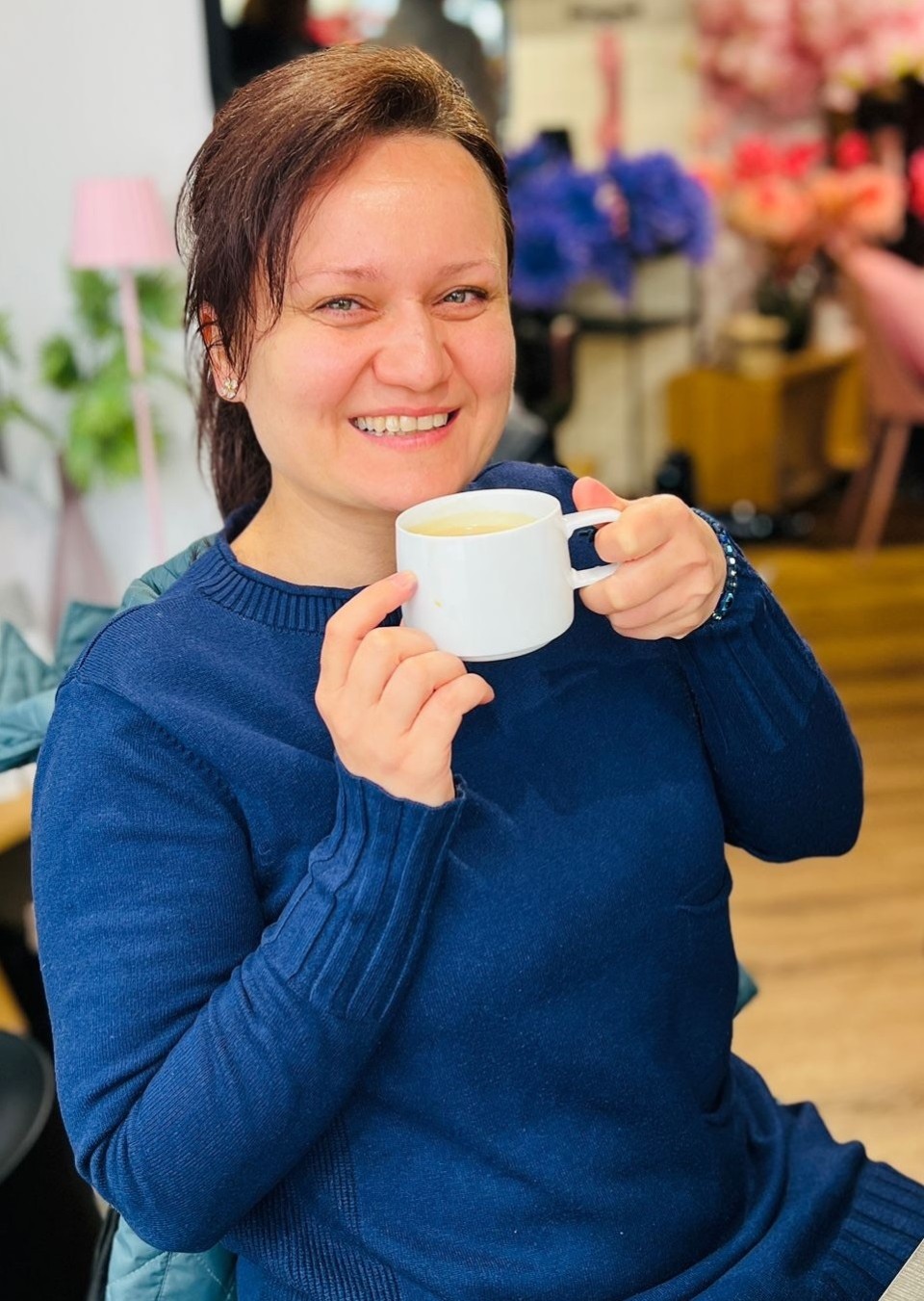 Eine Frau sitzt auf einem Stuhl und trinkt Kaffee.